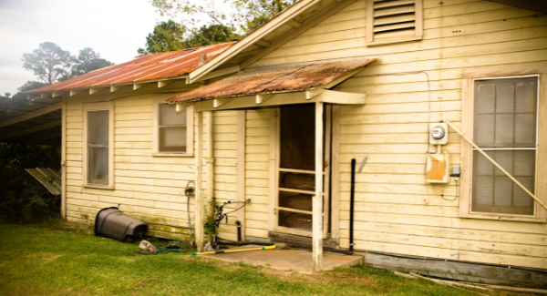 A distressed home with peeling paint and roof damage, which might be a great opportunity for a real estate investor.